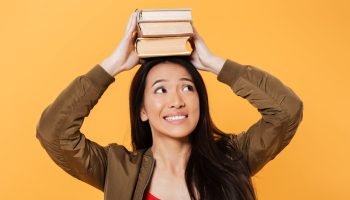 happy-asian-woman-jacket-holding-books-head (1)